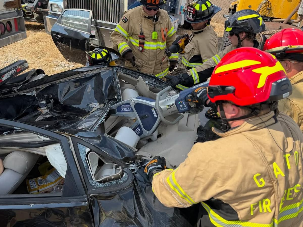 Firefighters using hydraulic rescue tools on a passenger vehicle during tractor-trailer extrication training