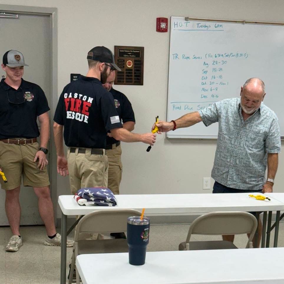 A Gaston member accepting a yellow knot while another member looks on