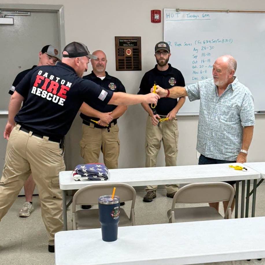 A Gaston member receiving a yellow knot with fellow divers standing behind him