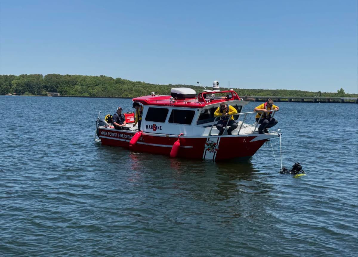 A public safety diver entering the water beside a fire department boat