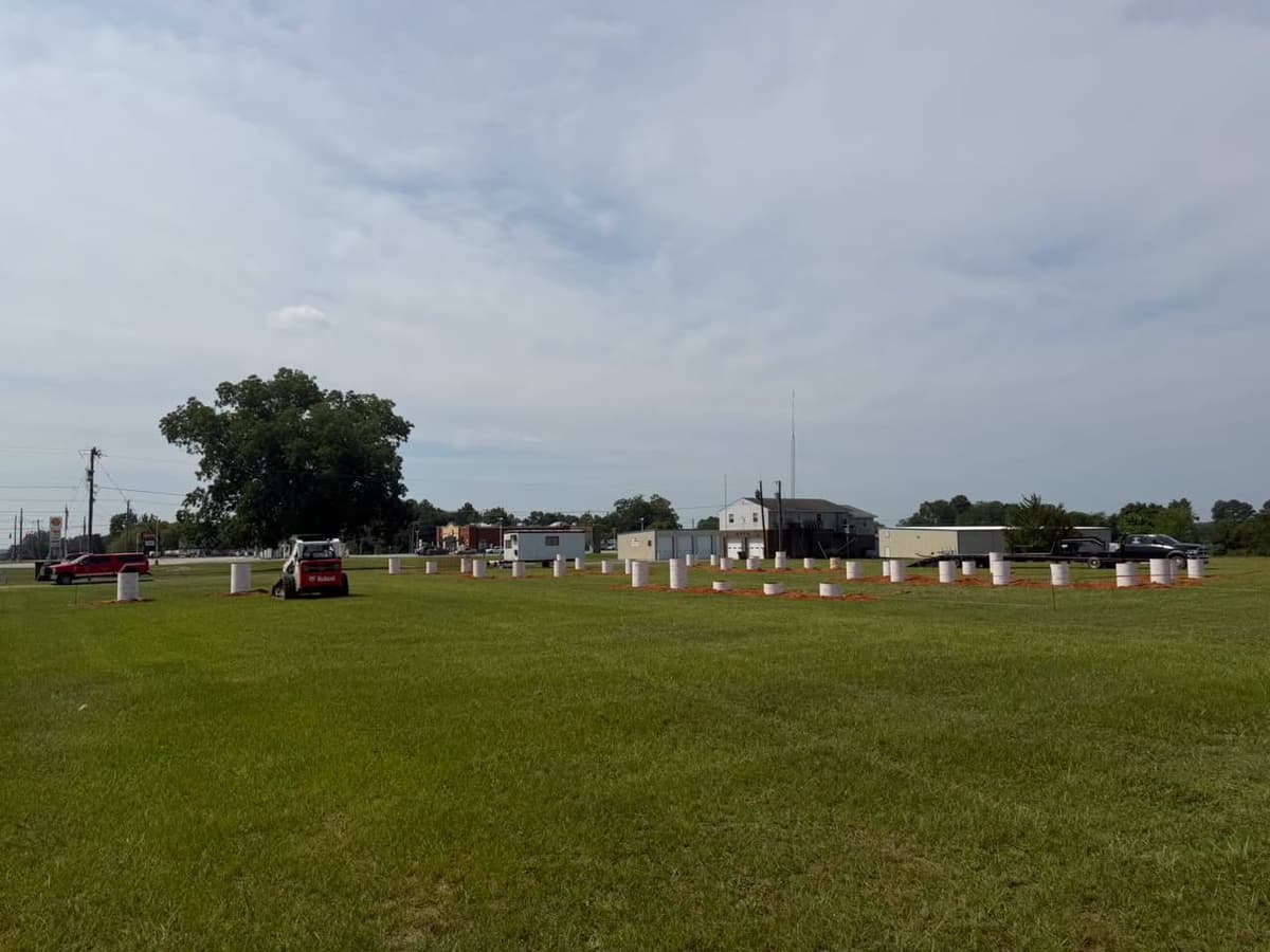 White barrels and orange layout markings across the grassy field at Gaston Fire and Rescue