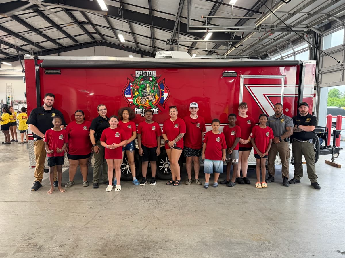 Campers and volunteers gather beside a Gaston fire engine